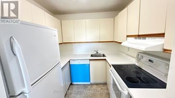 Ottawa condo for rent - A white refrigerator is in a kitchen with beige cabinets.
