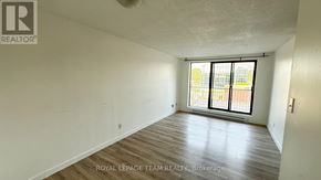 Ottawa condo for rent - A room with a ceiling fan and a window with a view of buildings outside.