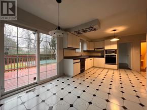 Toronto (St. Andrew-Windfields) apartment for rent - A spacious kitchen with white tiled flooring and a view of a red fence through the windows.