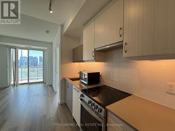 Toronto (Kensington-Chinatown) condo for rent - A kitchen with a black stove top oven and white cabinets.