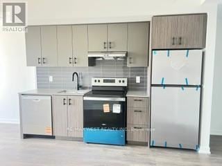 Burlington (Alton) condo for rent - A kitchen with a refrigerator, sink, and cabinets is being photographed for a realtor.