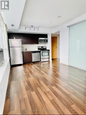 Toronto (South Parkdale) condo for rent - A kitchen with wooden floors and white walls.