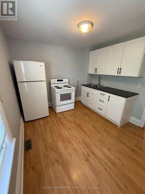 Hamilton (Stoney Creek) triplex for rent - A kitchen with white appliances and cabinets.