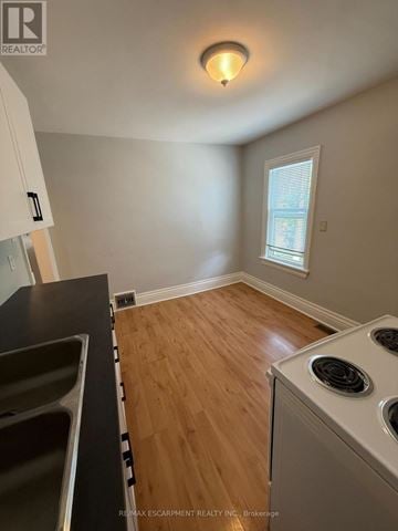 Hamilton (Stoney Creek) triplex for rent - A kitchen with a stove top oven and a window.