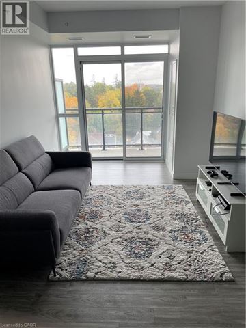 Waterloo condo for rent - A living room with a grey couch and a rug in front of a glass door.
