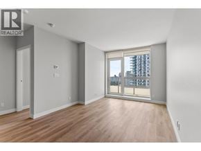 Coquitlam apartment for rent - A spacious room with wooden floors and a large window overlooking a cityscape.