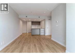 Coquitlam apartment for rent - A spacious room with wooden flooring and a kitchenette in the background.