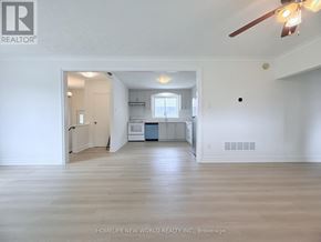 Toronto (Wexford-Maryvale) apartment for rent - A spacious room with a ceiling fan and a view of a kitchen in the background.