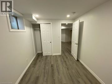 Brantford apartment for rent - A room with white walls and wood flooring, with a window on the left wall.