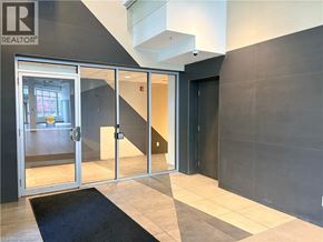 Waterloo condo for rent - A hallway with a black carpet and a glass door leading to a room.