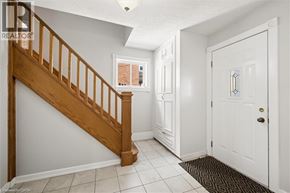 Kitchener apartment for rent - A hallway with a wooden staircase and a white door.