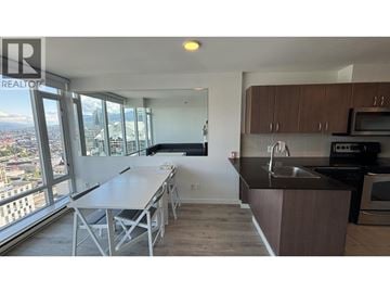 Vancouver apartment for rent - A kitchen with a table and chairs in front of a window with a view of the city.
