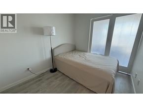 Vancouver apartment for rent - A bedroom with a bed, lamp, and sliding glass doors.
