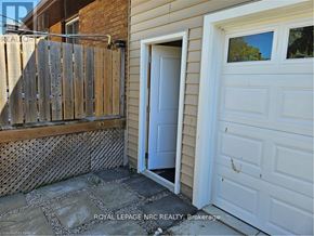 St. Catharines (Bunting/Linwell) apartment for rent - A white door is open to a small patio with a wooden fence.