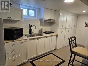 St. Catharines (Bunting/Linwell) apartment for rent - A kitchen with white cabinets and a black microwave.