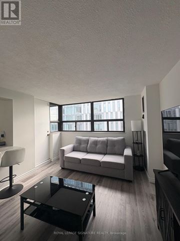 Toronto (Kensington-Chinatown) condo for rent - A living room with a grey couch and a black coffee table.