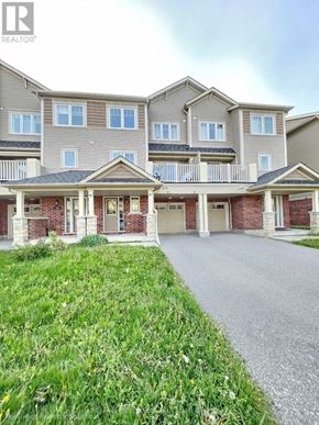 Oshawa (Windfields) townhouse for rent - A large, multi-story residential building with a grassy front yard.