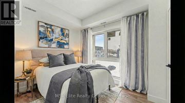 Niagara Falls (Arad/Fallsview) townhouse for rent - A bedroom with a large bed and a painting on the wall.