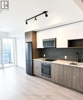 Toronto (Regent Park) house for rent - A modern kitchen with a black refrigerator and wooden cabinets.