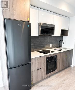 Toronto (Regent Park) house for rent - A modern kitchen with a black fridge and wooden cabinets.