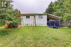 Toronto (Malvern) apartment for rent - A small house with a white exterior and a brown roof is surrounded by a grassy area with trees.