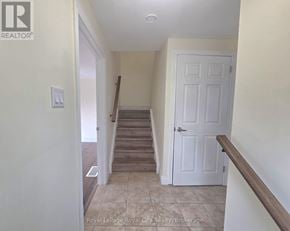 Guelph (Kortright West) apartment for rent - A hallway with a white door and a wooden staircase.
