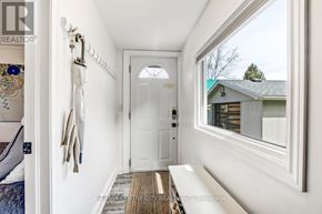 Central Elgin (Port Stanley) apartment for rent - A hallway with a white door and a window with a view of a tree.
