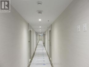 Brampton (Northwest Brampton) condo for rent - A long, narrow hallway with white walls and ceiling, and a series of doors on the right side.
