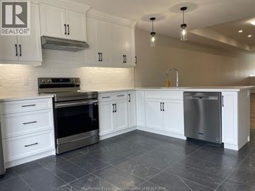 Essex townhouse for rent - A kitchen with white cabinets and a black stove top oven.