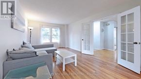 Mississauga (Erin Mills) apartment for rent - A living room with a grey couch, a glass coffee table, and a white door.