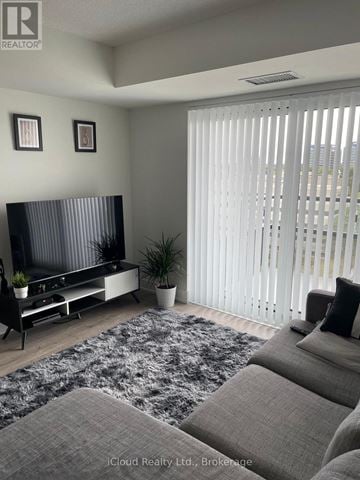 Toronto (Etobicoke West Mall) condo for rent - A living room with a grey sofa and a television.