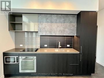 Vaughan (Vaughan Corporate Centre) condo for rent - A modern kitchen with black cabinets and a stainless steel oven.