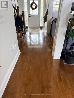 Cobourg townhouse for rent - A hallway with wooden floors and a white door.