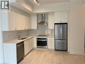 Kitchener condo for rent - A kitchen with white cabinets and a stainless steel refrigerator.
