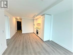 Toronto (Newtonbrook East) condo for rent - A spacious room with a kitchenette and a door leading to a darker room.
