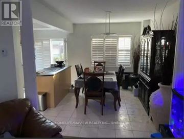 Toronto (Little Portugal) apartment for rent - A living room with a brown leather couch, a wooden dining table with chairs, and a kitchen area with a counter and sink.