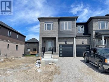 Barrie townhouse for rent - A real estate sign is displayed in front of a newly constructed house.