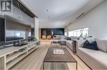 Oakville (Br Bronte) condo for rent - A modern living room with a large couch, a coffee table, and a flat-screen TV.