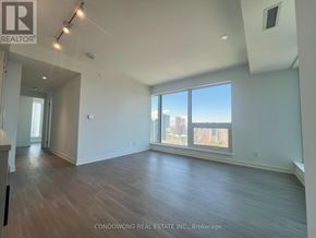 Toronto (Bay Street Corridor) condo for rent - A spacious room with wood flooring and large windows overlooking a cityscape.