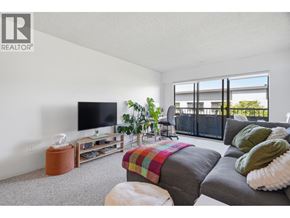 Vancouver apartment for rent - A living room with a grey couch, a television, and a window with a view of a balcony.