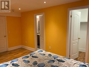 Caledon apartment for rent - A bedroom with a bed in the foreground and a yellow wall in the background.