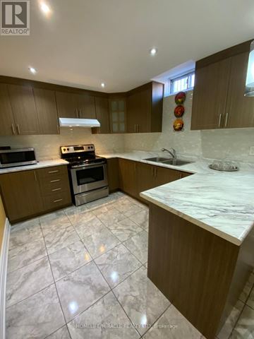 Caledon apartment for rent - A kitchen with brown cabinets and a marble countertop.