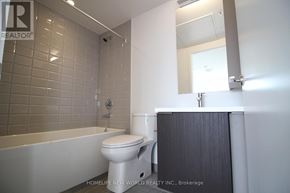Toronto (Kensington-Chinatown) condo for rent - A white toilet sits in a bathroom with a white tub and a white shower curtain.