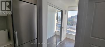 Toronto (Kensington-Chinatown) condo for rent - A stainless steel refrigerator in a kitchen with a window showing a view of a city.