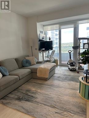 Richmond Hill (Langstaff) condo for rent - A living room with a grey couch, a television, and a large window.