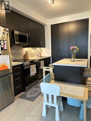 Richmond Hill (Langstaff) condo for rent - A kitchen with a fridge, microwave, oven, and a table with a vase of flowers on it.