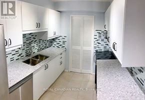 Toronto (Eglinton East) condo for rent - A kitchen with white cabinets and a black and white tiled backsplash.