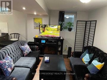 Brampton (Sandringham-Wellington) apartment for rent - A living room with a black couch and a television.