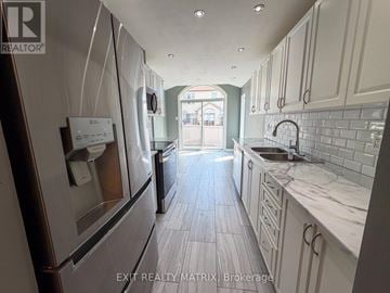 Ottawa townhouse for rent - A modern kitchen with white cabinets and a marble countertop.