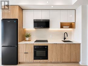 Toronto (Regent Park) condo for rent - A modern kitchen with wooden cabinets and black appliances.